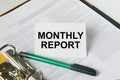 Text Monthly Report on a white card that is in a folder with documents and a green pen Royalty Free Stock Photo