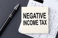 Text NEGATIVE INCOME TAX on sticker on calculator, business concept