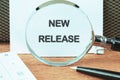 Text NEW RELEASE on a white sheet through a magnifying glass, close-up Royalty Free Stock Photo