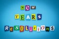 Text - New year`s resolutions. Cut colorful letters on blue background. Writing on banner, card. Inscription, message on poster.