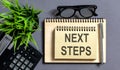 Text Next Steps on notepad with office tools, pen Royalty Free Stock Photo
