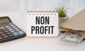 Text NON PROFIT on stickers. Clipboard with charts, pen, piggy bank and calculator on blue background. Royalty Free Stock Photo