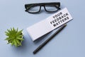 Text on notepad with reading glasses and potted plant on blue background
