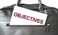 Text OBJECTIVES writing on white paper sheet in the black business bag. Business concept