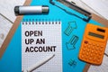 Text OPEN UP AN ACCOUNT on white paper on clipboard with chart and calculator. Royalty Free Stock Photo