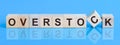 The text OVERSTOCK is written on the cubes in black letters, the cubes are located on a blue glass surface