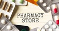 Text PHARMACY STORE on a white background. Nearby are various medicines. Medical concept