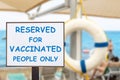 Text plate RESERVED FOR VACCINATED PEOPLE ONLY at luxury hotel sea beach resort area empty loungers on summer day. New Royalty Free Stock Photo