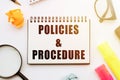 Text POLICIES&PROCEDURE in notebook on white table with office tools