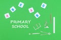 Text primary school, from above wooden minitures school supplies and abc letters on green background