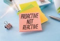 Text Proactive not reactive on white paper book on table, business concept.