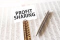 Text profit sharing on paper card, pen, financial documentation on table - business