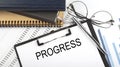 Text PROGRESS on Office desk table with notebooks, supplies,analysis chart, on the white background Royalty Free Stock Photo