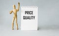 Text about quality and price on a notebook, next to a wooden doll. Low price and high quality service Royalty Free Stock Photo