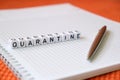 Text `Quarantine`, word made of cubic letters and luxury pen on a white paper note pad background.