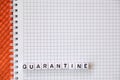 Text `Quarantine`, word made of cubic letters on a white paper note pad background.