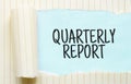 The text QUARTERLY REPORT appearing behind torn white paper Royalty Free Stock Photo