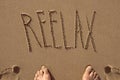 Text reelax written in the sand of a beach
