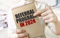 Text REFERRAL PROGRAM 2024 on brown paper notepad in businessman hands in office. Business concept Royalty Free Stock Photo