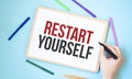 Text Restart Yourself on a notebook surrounded by colored felt-tip pens, business concept idea