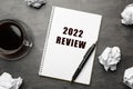 Text 2022 Review written in notebook, pen, cup of coffee and crumpled paper balls on grey table, flat lay Royalty Free Stock Photo