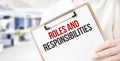 Text roles and responsibilities on white paper plate in businessman hands in office. Business concept