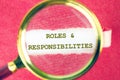 Text Roles and Responsibility through a magnifying glass under a torn paper Royalty Free Stock Photo