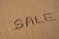 Text SALE handwritten in sand surface. Concept of promotion Black Friday Blue ocean wave washing away message at the Royalty Free Stock Photo