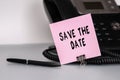 The text Save the date written on a pink sticky note to remind you an important event. Closeup of a personal agenda Royalty Free Stock Photo