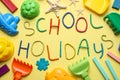 Text School Holidays made of modelling clay and different sand toys on background, flat lay Royalty Free Stock Photo