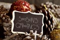 Text seasons greetings, pine cones and baubles