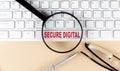 Text SECURE DIGITAL on keyboard with magnifier , glasses and pen on beige background Royalty Free Stock Photo