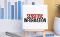 text Sensitive Information on easel with office tools and paper.Top view Royalty Free Stock Photo