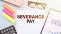 The text - Severance Pay on office desk with calculator, markers, glasses and financial charts