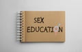 Text Sex Education with female and male gender signs instead of letter O in notebook on light background, top view