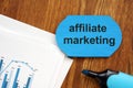 Text sign showing affiliate marketing. The text is written on a small wooden board. Graphs on the paper sheet, markers, wooden Royalty Free Stock Photo