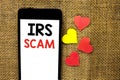 Text sign showing Irs Scam. Conceptual photo Warning Scam Fraud Tax Pishing Spam Money Revenue Alert Scheme written on Cardboard P