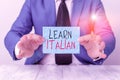 Text sign showing Learn Italian. Conceptual photo gain or acquire knowledge of speaking and writing Italian Man holds empty paper Royalty Free Stock Photo