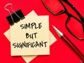 Text SIMPLE BUT SIGNIFICANT on paper notes with pen and eye glasses isolated on red background.