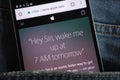 Text about Siri on Apple website displayed on smartphone hidden in jeans pocket