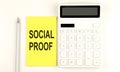 Text SOCIAL PROOF on yellow sticker, next to pen and calculator