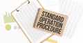 Text Standard Operation Procedure on brown paper notepad on the table with diagram. Business concept Royalty Free Stock Photo