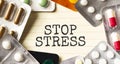 Text STOP STRESS on a white background. Nearby are various medicines. Medical concept