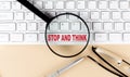 Text STOP AND THINK on keyboard with magnifier , glasses and pen on beige background Royalty Free Stock Photo