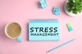 Text Stress Management in notebook on pink background with stationery and cup of coffee, flat lay Royalty Free Stock Photo