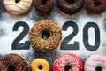 Text 2020 surrounded by colorful donuts on a black background vintage, new year concept.