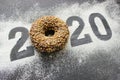 Text 2020 surrounded by colorful donuts on a black background vintage, new year concept.
