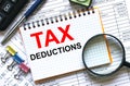 Text Tax Deductions on notepad with calculator, clips, pen on financial report