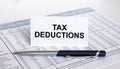 Text Tax Deductions on white card with blue metal pen on financial table