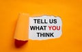 The text `tell us what you think` appearing behind torn orange paper. Business concept. Copy space Royalty Free Stock Photo